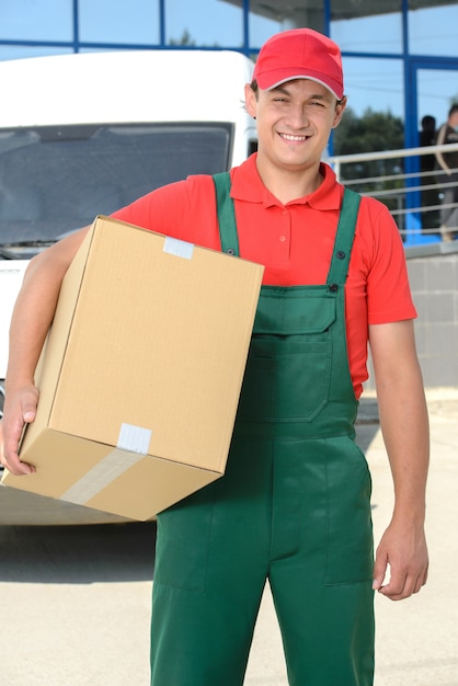 Giovane uomo maschio sorridente del corriere di consegna postale.