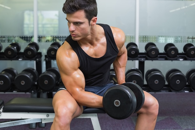 Giovane uomo muscolare che si esercita con il dumbbell