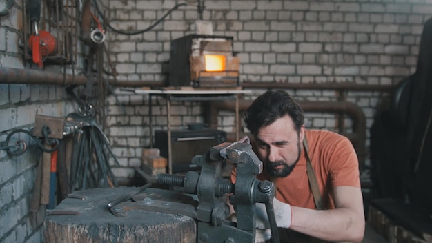 Giovane uomo muscoloso che lavora su un fabbro con metallo, grandangolo