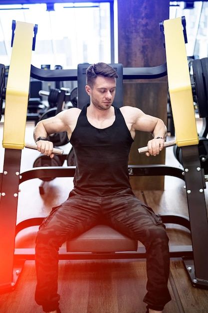 Giovane uomo muscoloso che si allena duramente in palestra Bell'uomo con un bel allenamento bicipite