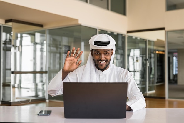 Giovane uomo musulmano africano che utilizza il computer portatile in ufficio