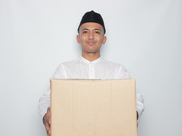 Giovane uomo musulmano asiatico che viaggia da solo mudik per eid mubarak lebaran e porta una scatola isolata
