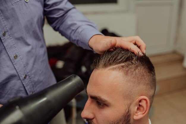 Giovane uomo nel concetto di servizio di cura dei capelli del barbiereGiovane uomo nel concetto di servizio di cura dei capelli del barbiere