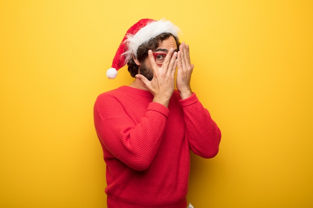 Giovane uomo pazzo barbuto che indossa occhiali rossi e cappello di Babbo Natale