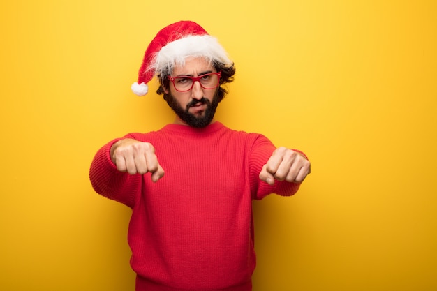 Giovane uomo pazzo barbuto che indossa occhiali rossi e cappello di Babbo Natale