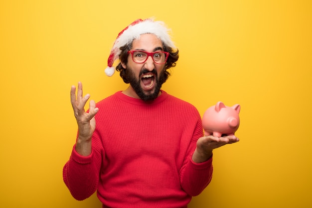 Giovane uomo pazzo barbuto che indossa occhiali rossi e cappello di Babbo Natale