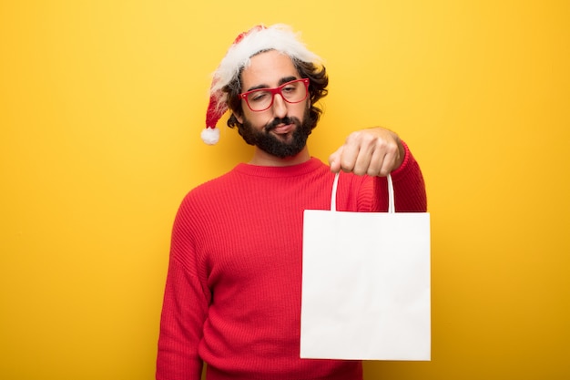 Giovane uomo pazzo barbuto che indossa occhiali rossi e cappello di Babbo Natale