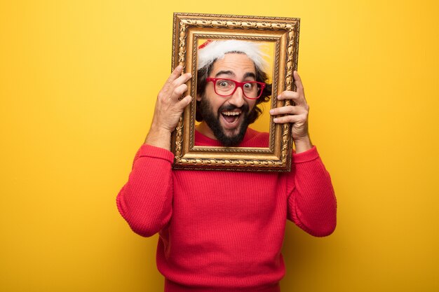 Giovane uomo pazzo barbuto che indossa occhiali rossi e cappello di Babbo Natale