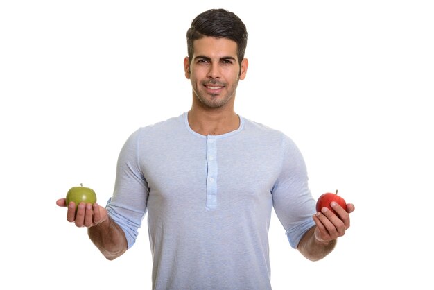 Giovane uomo persiano felice che sorride mentre tiene la mela rossa e verde