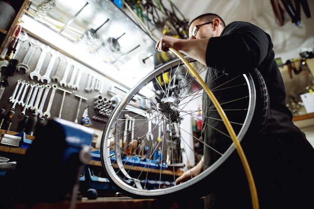 Giovane uomo professionale che prepara pompare aria nella ruota di bicicletta.