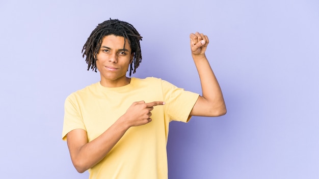 Giovane uomo rasta afroamericano che mostra gesto di forza con le braccia, simbolo del potere femminile