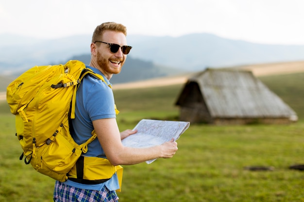 Giovane uomo redhair sull'escursione della montagna che tiene una mappa