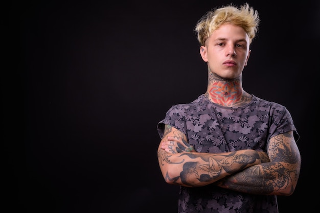 Giovane uomo ribelle bello con capelli biondi e tatuaggi