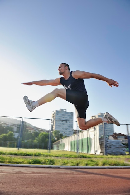 giovane uomo sano correre su pista sportiva da corsa atletica e che rappresenta il concetto di ordinamento e velocità