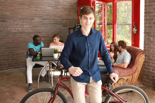 Giovane uomo seduto su una bicicletta in un ufficio moderno