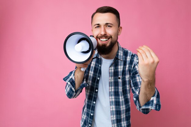 Giovane uomo sorridente bello con la barba usando il megafono