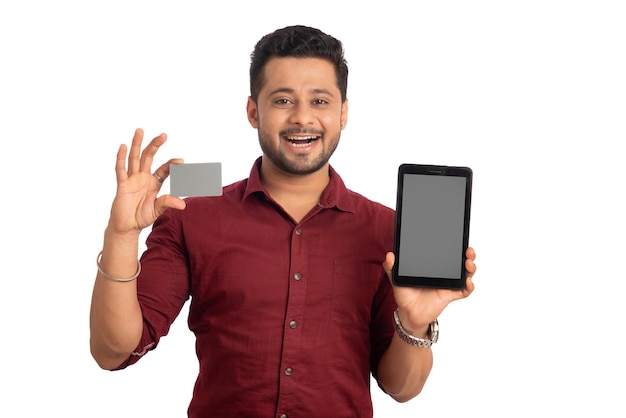 Giovane uomo sorridente che presenta una carta di credito mentre utilizza uno smartphone o acquista online sul cellulare con una carta di credito