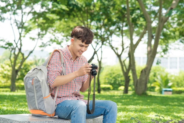 Giovane uomo sorridente che scatta foto mentre si cammina nel parco