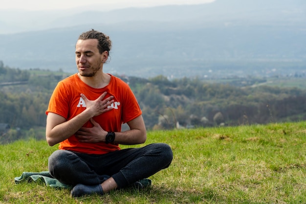 Giovane uomo sorridente seduto sulla cima della montagna