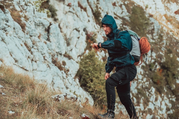 Giovane uomo sportivo all'aperto guardando orologio cardiofrequenzimetro Giovane escursionista sentiero escursione sulla montagna