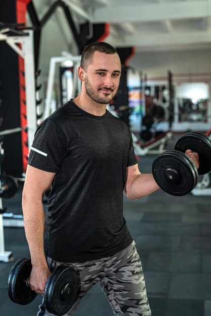 Giovane uomo sportivo che fa esercizio con il manubrio in palestra