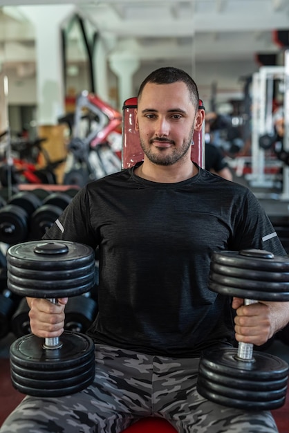 Giovane uomo sportivo che fa esercizio con il manubrio nel concetto di esercizi di peso in palestra