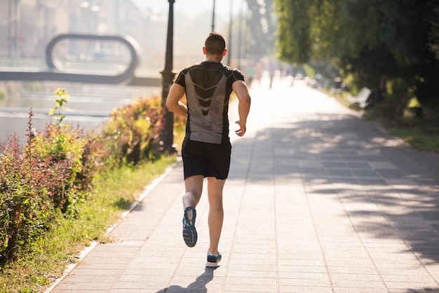 giovane uomo sportivo che fa jogging al mattino soleggiato in città