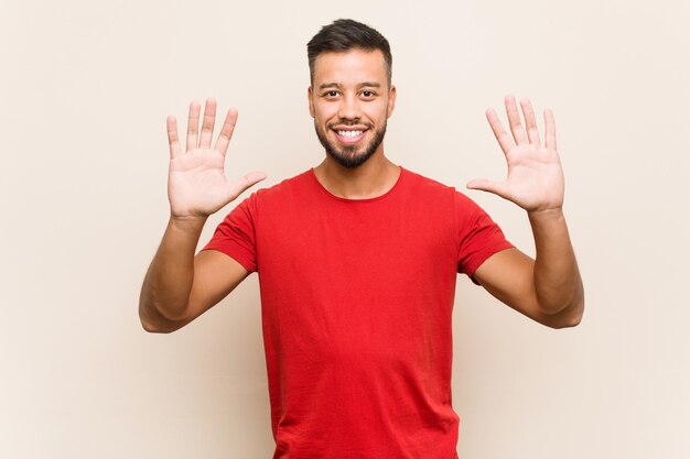 Giovane uomo sud-asiatico che mostra numero dieci con le mani.