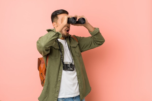 Giovane uomo sud-asiatico che osserva tramite un binocolo.