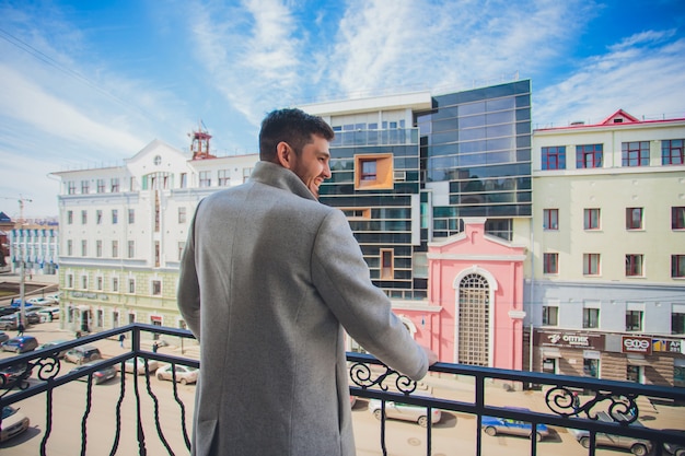 Giovane uomo sul balcone contro edifici