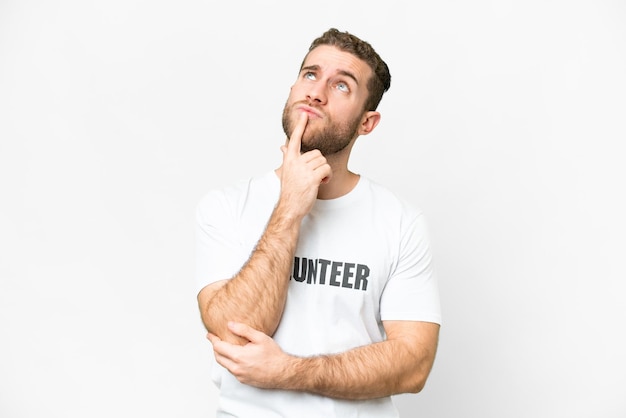 Giovane uomo volontario su sfondo bianco isolato che ha dubbi mentre guarda in alto