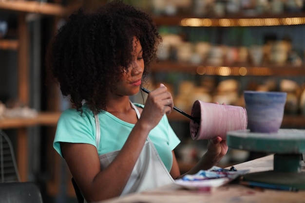 Giovane vasaio afro ragazza mano che fa vaso di argilla in laboratorio di ceramica, imprenditore.