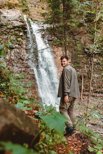 Giovane viandante dell'uomo forte che guarda lo spazio della copia della cascata