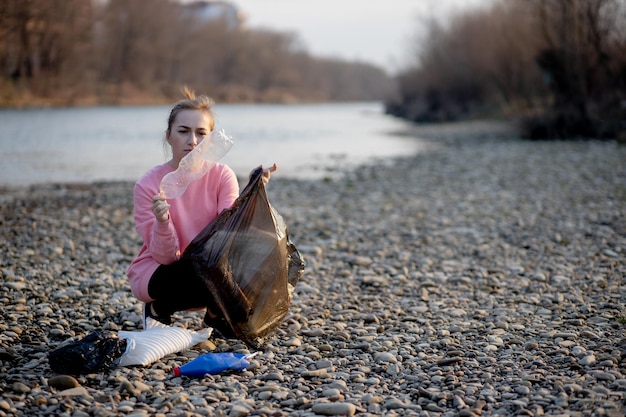 Giovane volontaria che raccoglie immondizia sul fiume.