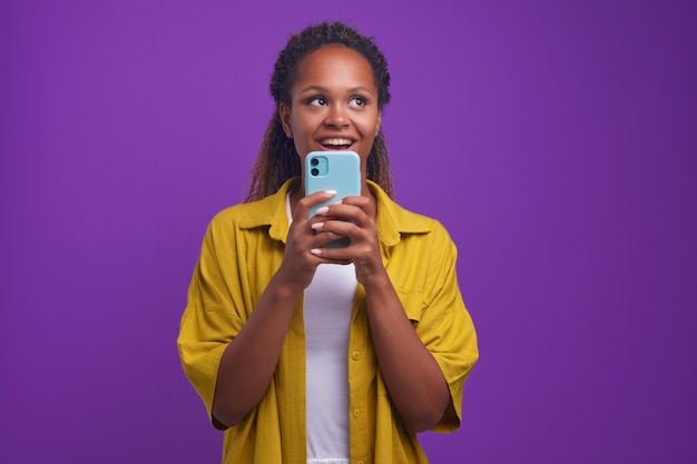 Giovane zoomer donna afroamericana casuale felice con il telefono cellulare in mano
