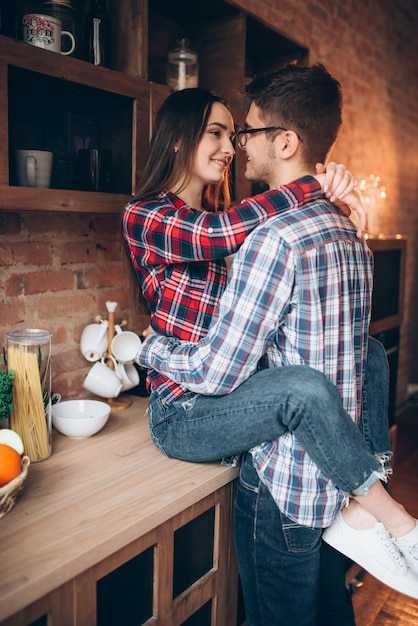 Giovani abbracci delle coppie di amore sulla cucina