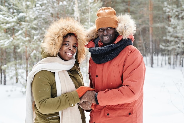 Giovani affettuose coppie afroamericane in abbigliamento invernale che si tengono per mano