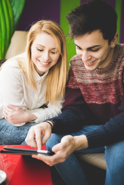 giovani amanti della bella coppia seduti al bar utilizzando tablet wireless collegato online