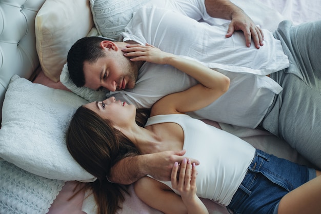 Giovani amanti uomo e donna in camera da letto sul letto.