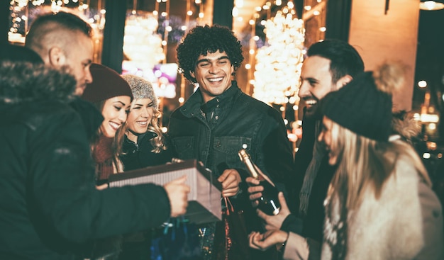Giovani amici allegri che si divertono alla festa all'aperto di Natale nella strada della città di notte.