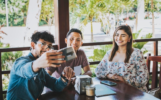 Giovani amici che si fanno un selfie in una caffetteria Tre persone felici in una caffetteria che si fanno un selfie Vista frontale di amici adolescenti che si fanno un selfie e si divertono in un ristorante caffetteria