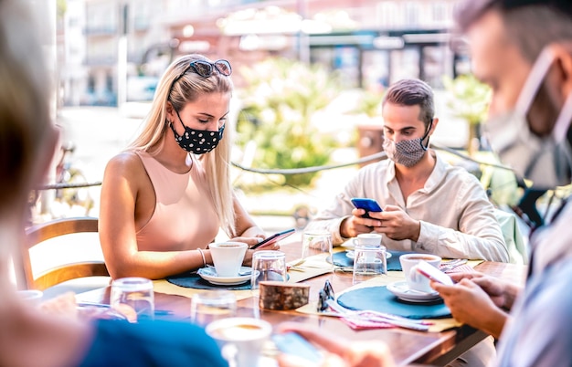 Giovani amici che utilizzano telefoni cellulari intelligenti al bar