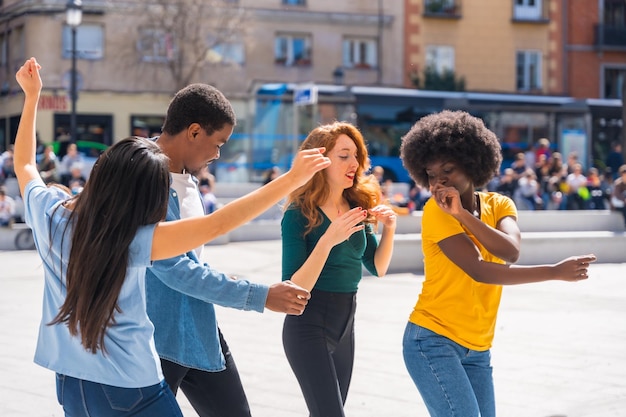 Giovani amici multietnici che ballano in città autentico gruppo di amici diversi che si divertono