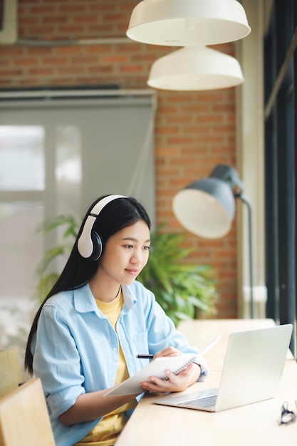 Giovani asiatici che imparano online usando il laptop al tavolo
