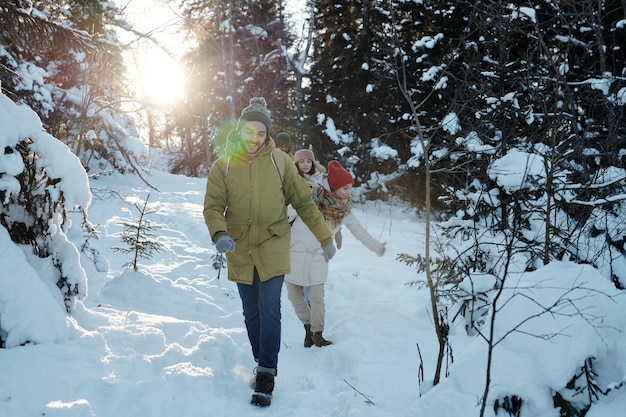 Giovani backpackers felici che si spostano verso il basso il cumulo di neve nella foresta