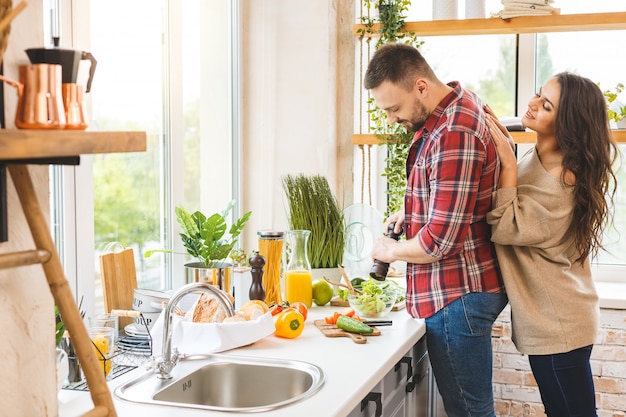 Giovani belle coppie che cucinano insieme nella loro cucina a casa.