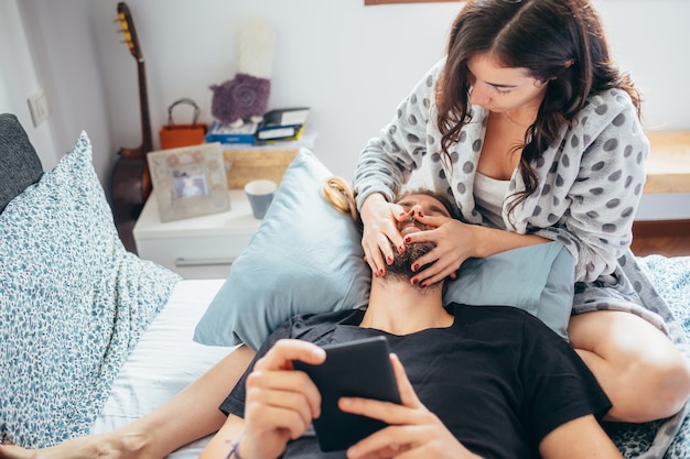 Giovani belle coppie felici nell'amore che si trova sul letto che stringe a sé facendo uso della compressa