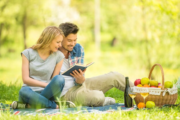 Giovani belle coppie vestite casual avendo picnic nel parco.