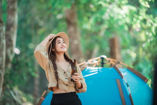 Giovani belle donne asiatiche e amici viaggiatori che si rilassano davanti alla tenda da campeggio Si divertono a parlare e bere birra divertendoti e felici insieme