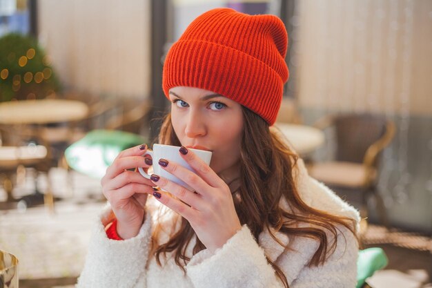 Giovani belle donne dai capelli scuri bevono caffè in un caffè e fanno acquisti online di regali di Natale Vacanze invernali Capodanno